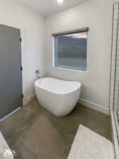 Bathroom with a washtub, concrete floors, and baseboard heating