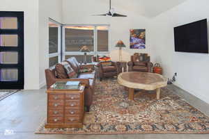 Living room with ceiling fan, vaulted ceiling, and concrete floors