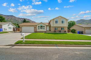 Tri-level home featuring a front lawn, a mountain view, and a garage