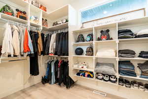 Spacious closet with light hardwood / wood-style flooring