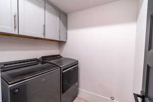 Washroom featuring light hardwood / wood-style flooring, separate washer and dryer, and cabinets