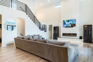 Living room with light hardwood / wood-style floors and a high ceiling