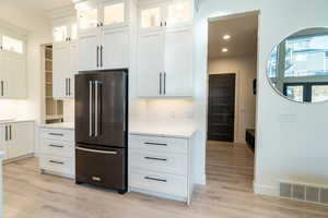 Kitchen featuring white cabinets, light hardwood / wood-style flooring, and high quality fridge