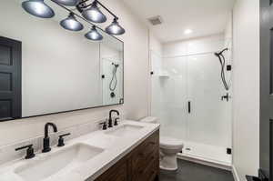 Bathroom featuring an enclosed shower, toilet, vanity, and tile patterned floors