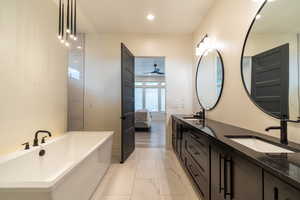 Bathroom with ceiling fan, a bathtub, vanity, and hardwood / wood-style floors