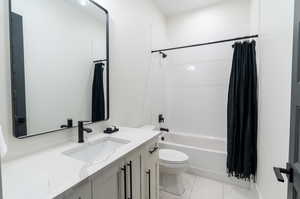 Full bathroom featuring tile patterned floors, toilet, shower / tub combo with curtain, and vanity