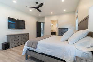 Bedroom featuring light wood-type flooring, connected bathroom, and ceiling fan