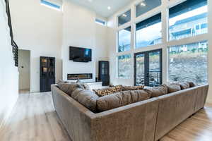 Windows for days allowing glorious amounts of light into the living room. Living room with a high ceiling, light hardwood / wood-style floors, and french doors