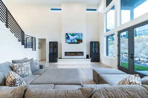 Living room featuring a high ceiling, plenty of natural light, french doors, and wood-type flooring