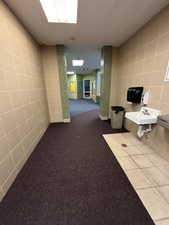 Corridor featuring sink, tile walls, and light tile patterned floors