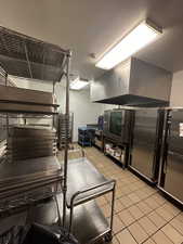 Kitchen with light tile patterned floors and high end fridge