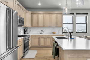 Kitchen featuring light hardwood / wood-style floors, sink, a center island with sink, light brown cabinets, and high end appliances