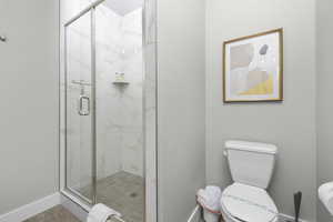 Bathroom featuring a shower with shower door and toilet