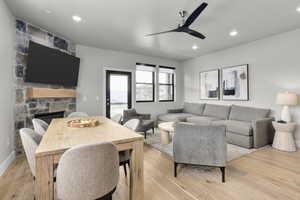 Living room featuring light hardwood / wood-style floors, a stone fireplace, and ceiling fan