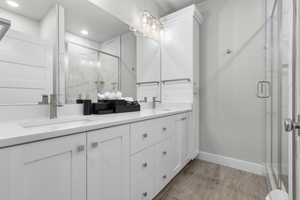 Bathroom featuring hardwood / wood-style floors, vanity, and a shower with shower door