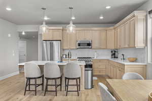 Kitchen with light hardwood / wood-style flooring, light brown cabinetry, and premium appliances