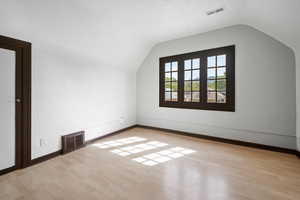 Additional living space with light hardwood / wood-style flooring and lofted ceiling