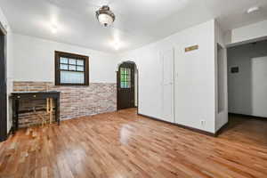 Unfurnished living room featuring light hardwood / wood-style floors, brick wall, and a fireplace