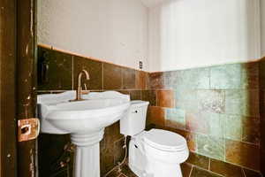 Bathroom featuring tile walls, tasteful backsplash, tile patterned floors, and toilet