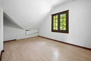 Additional living space featuring light wood-type flooring and lofted ceiling