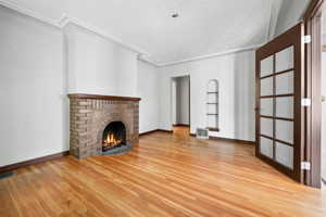 Unfurnished living room featuring a fireplace, light hardwood / wood-style flooring, built in features, and crown molding