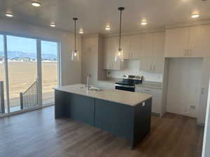 Kitchen featuring a mountain view, a center island with sink, decorative light fixtures, and stainless steel range with electric stovetop