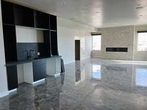 Basement living room featuring a large fireplace, a healthy amount of sunlight, and Wetbar