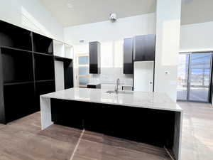 Kitchen with light stone counters, dark cabinets, walnut hardwood floors