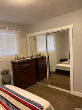 Bedroom featuring a closet, a textured ceiling, and dark carpet