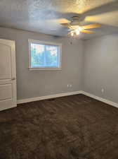 Spare room featuring carpet floors, ceiling fan, and a textured ceiling