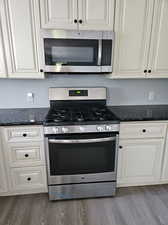 Kitchen featuring hardwood / wood-style floors, stainless steel appliances, and white cabinets