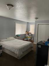 Bedroom with carpet floors, a textured ceiling, a closet, and black refrigerator