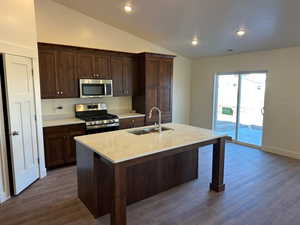 Kitchen with appliances with stainless steel finishes, sink, dark hardwood / wood-style floors, and lofted ceiling