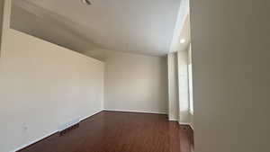 Unfurnished room featuring dark hardwood / wood-style flooring and vaulted ceiling