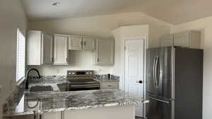 Kitchen featuring appliances with stainless steel finishes, a wealth of natural light, lofted ceiling, and sink