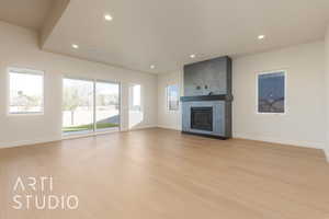 Unfurnished living room with light wood-type flooring and a large fireplace