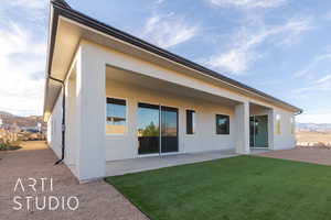 Back of house featuring a mountain view, a patio area, and a lawn