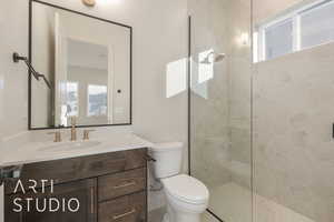 Bathroom featuring vanity, toilet, and tiled shower