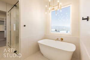 Bathroom featuring an inviting chandelier, tile patterned floors, a mountain view, independent shower and bath, and tile walls