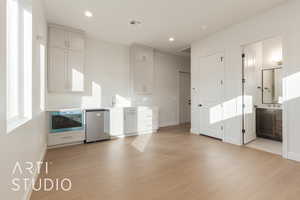 Kitchen with dishwasher, white cabinets, sink, light hardwood / wood-style flooring, and built in microwave