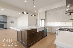 Kitchen featuring pendant lighting, a kitchen island with sink, white cabinets, appliances with stainless steel finishes, and light hardwood / wood-style floors