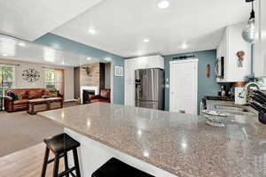 Kitchen with tile floors, white cabinetry, stone counters, appliances with stainless steel finishes, and a textured ceiling