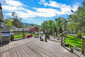 Wooden deck with a mountain view, area for grilling, a shed, and a lawn