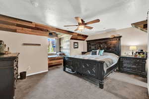 Carpeted bedroom featuring ceiling fan, a textured ceiling.