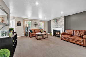 Carpeted living room featuring a textured ceiling and a large fireplace