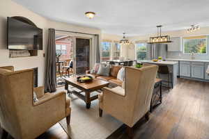 Living room featuring a wealth of natural light, sink, a notable chandelier, and dark hardwood / wood-style floors