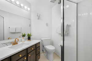 Bathroom with tile patterned flooring, an enclosed shower, vanity, and toilet