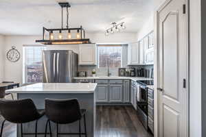 Kitchen featuring decorative backsplash, dark hardwood / wood-style floors, appliances with stainless steel finishes, a textured ceiling, and a center island