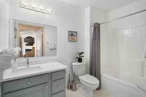 Full bathroom with tile patterned floors, vanity, shower / bath combo, and toilet