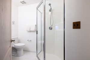 Bathroom with tile patterned floors, toilet, and an enclosed shower